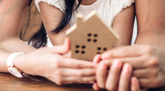 Eine Familie hält ein kleines Haus in der Hand