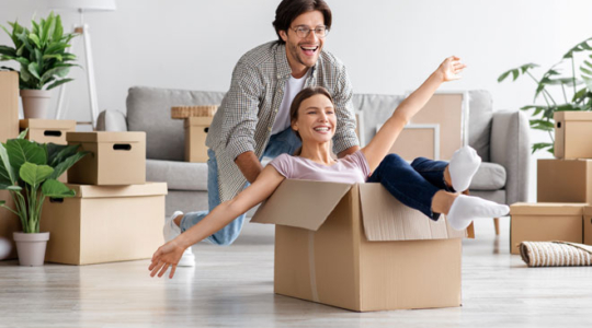 Immobilienkauf | Junges Paar im Wohnzimmer mit zahlreichen Umzugskartons