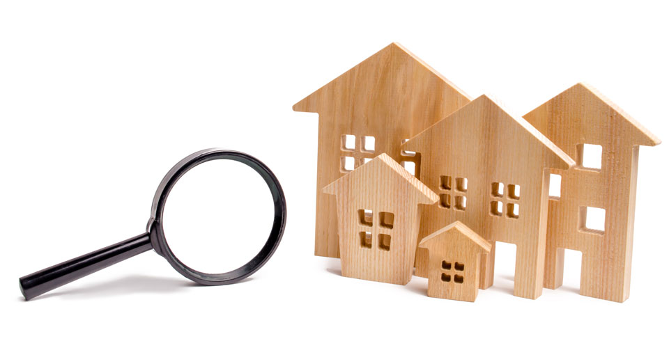 Immobiliensuche | Modellhäuser aus Holz mit Lupe
